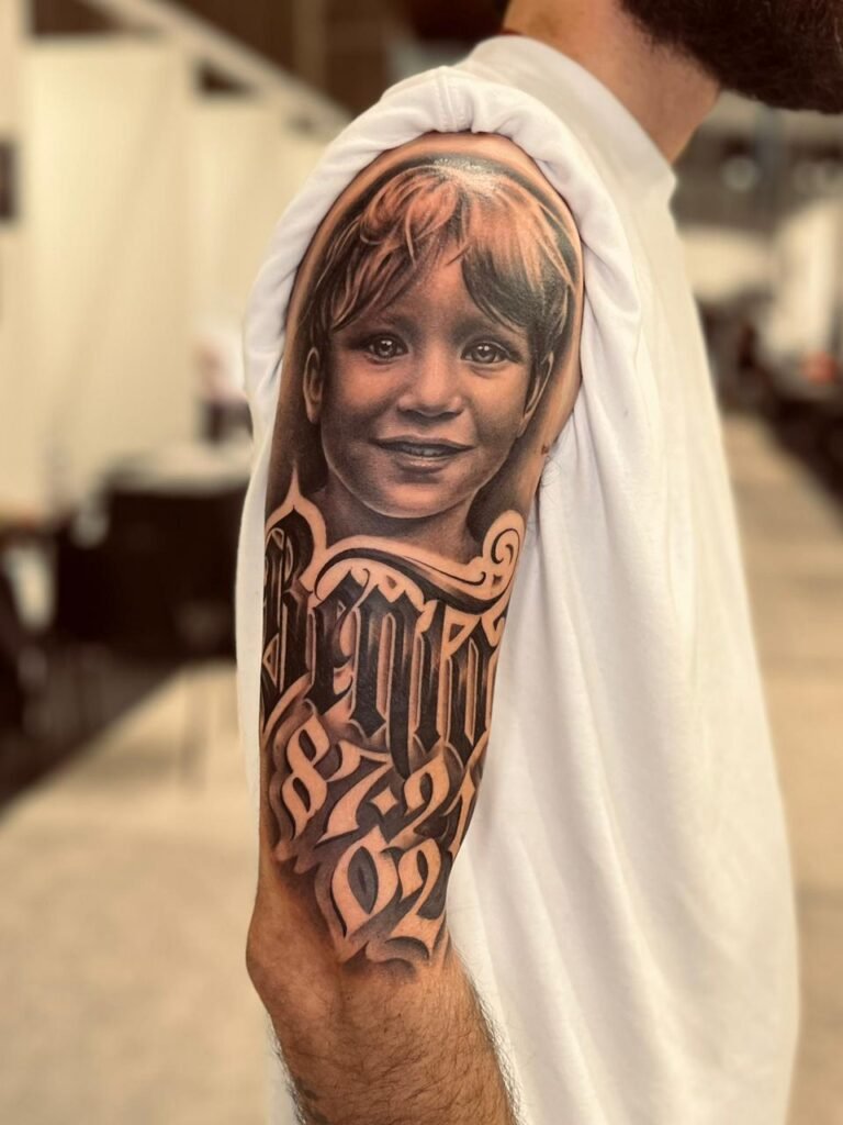Realistic black and grey child portrait tattoo with custom lettering by Yago Sousa
